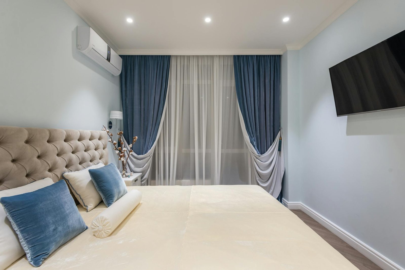 Interior of cozy bedroom with soft bed and blue cushions and curtains